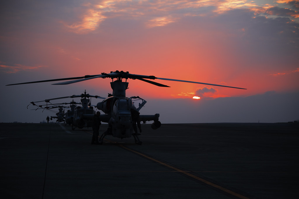 Military helicopters parked on a flight line at sunset